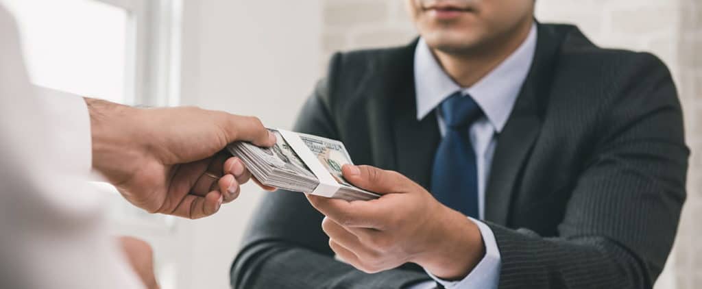 Man in suit giving cash to another person