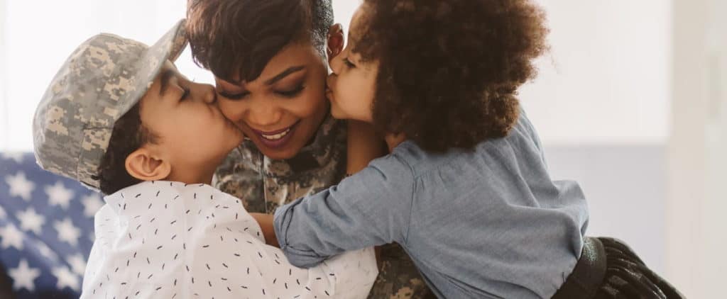 Military mother in uniform hugging her children