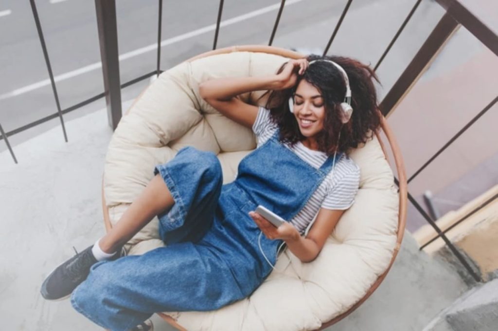 Girl laying in plush chair listening to music on her phone